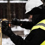 Worker installing a Reconeyez wireless security sensor at a construction site