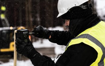 Worker installing a Reconeyez wireless security sensor at a construction site