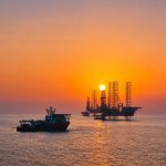 Offshore drilling rigs at sunset representing ADNOC’s AI-enabled drilling operations in the UAE